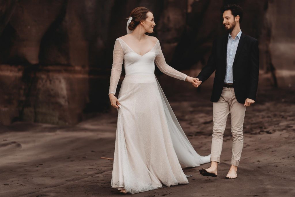 bride and groom walking in photo session at Muriwai Beach - Auckland Wedding Photographer