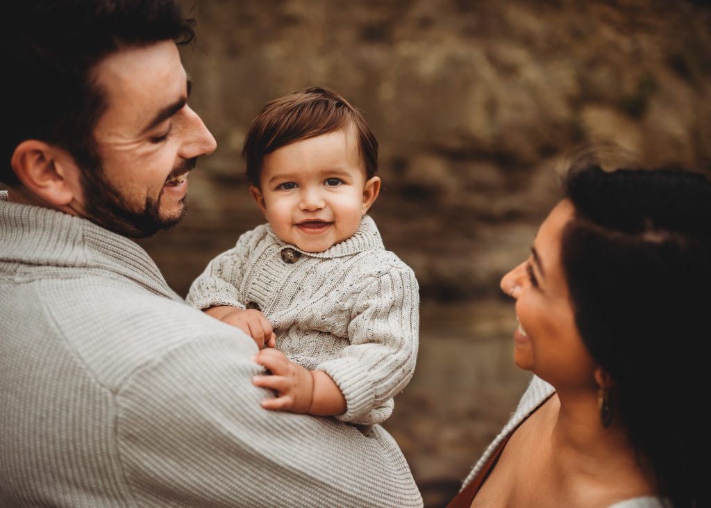 one year old boy smiling with his parents