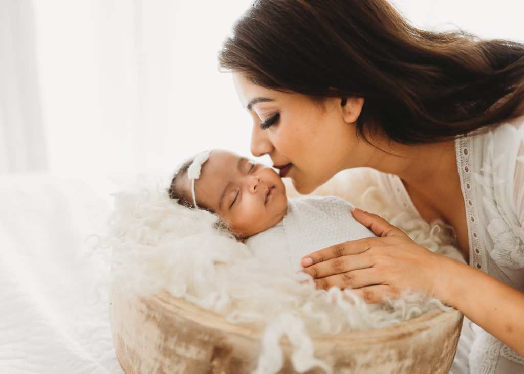 mother kissing newborn cheeks