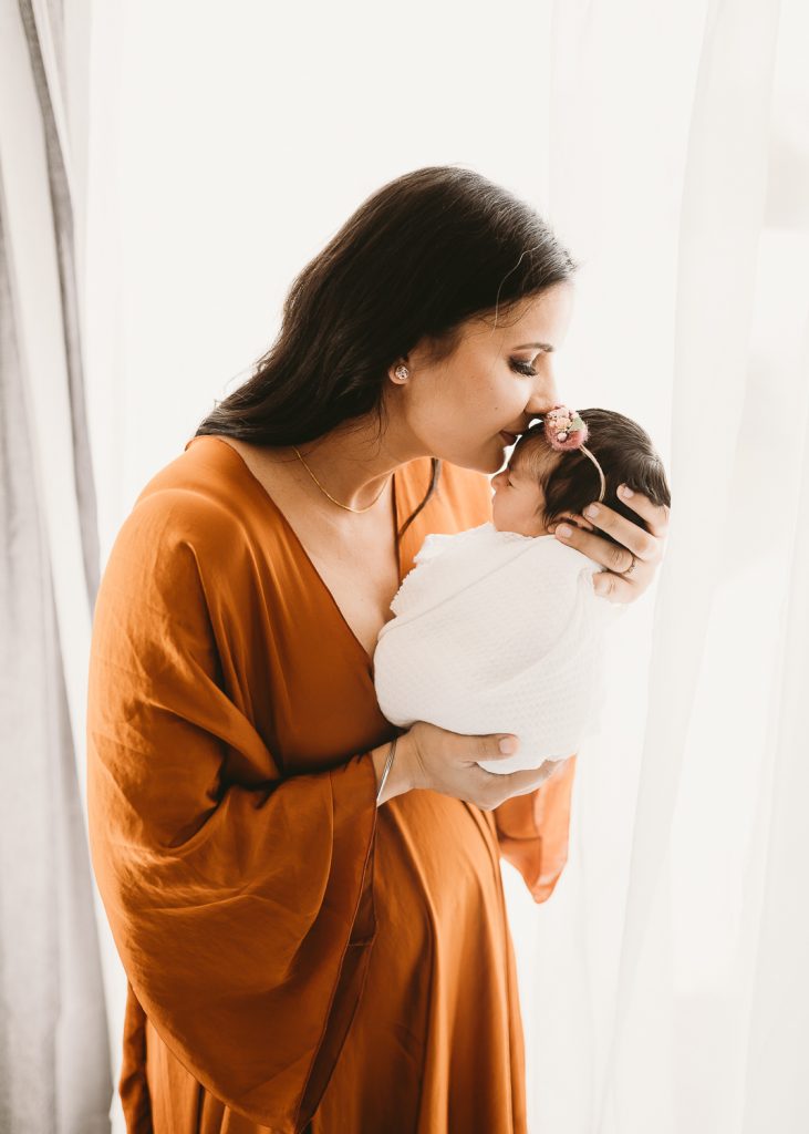 mum kissing newborn