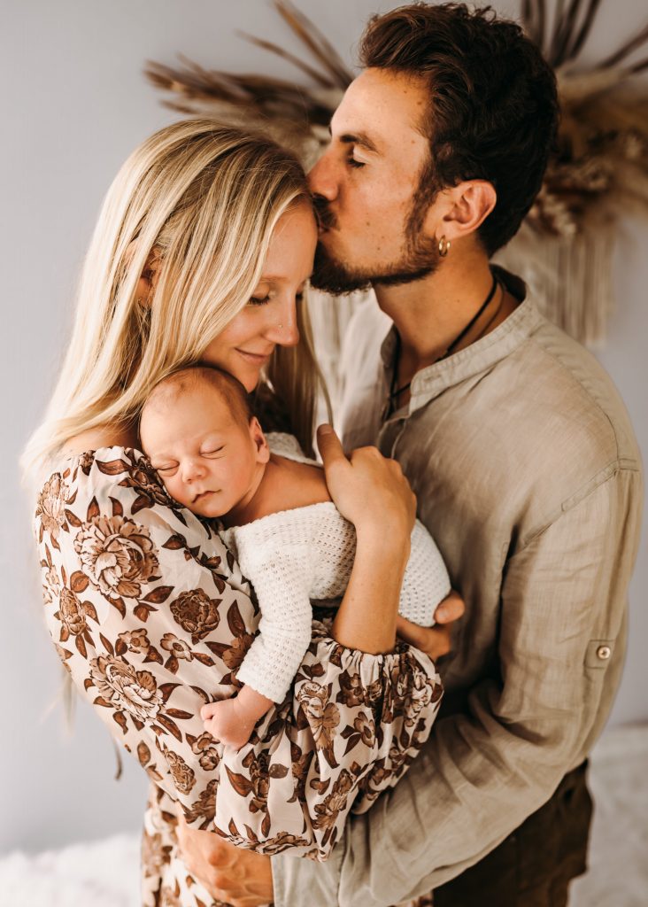 Father kissing mother with a baby