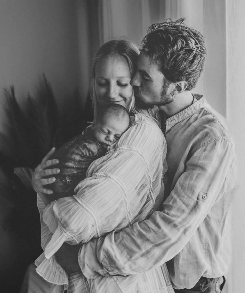 mother smiling and baby boy and father are with her