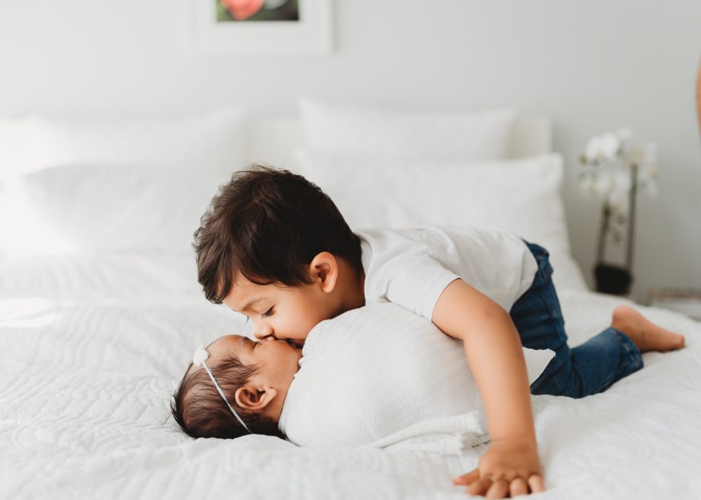 brother kissing newborn