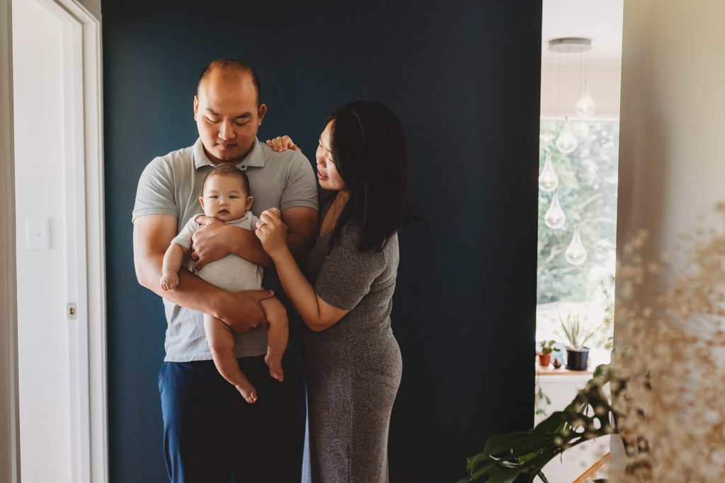 father holding newborn with mother - Auckland Lifestyle Newborn Photographer Amber Farooq