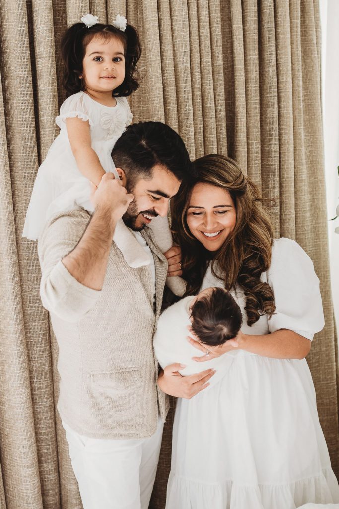 mother father hugging standing near new one - Auckland Lifestyle Newborn Photography Amber Farooq