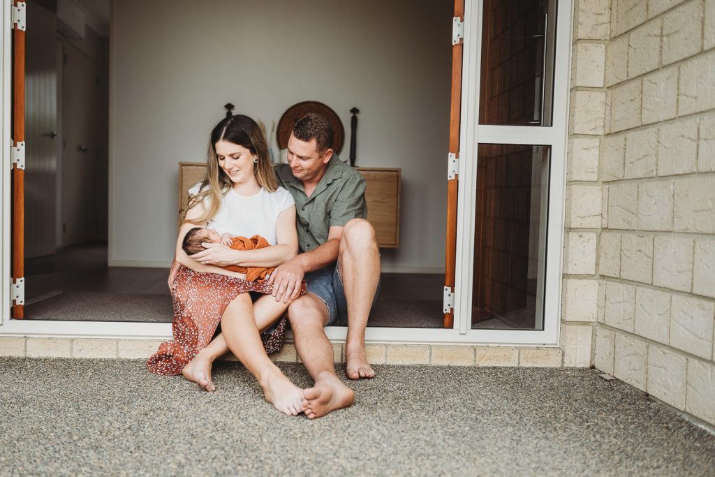 Mother and father sitting on the porch holding their newborn - Auckland Lifestyle Newborn Photographer Amber Farooq