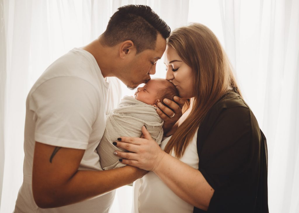 mother father kissing newborn – Auckland studio newborn photographer