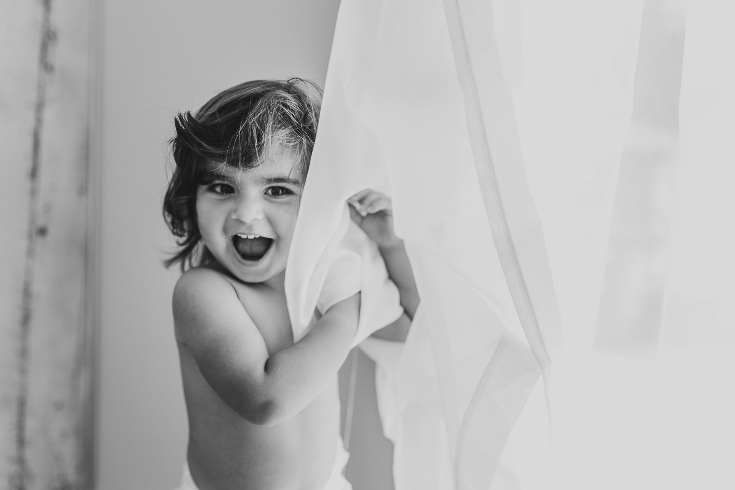 baby girl hiding behind curtain - cake smash photographer auckland Amber Farooq