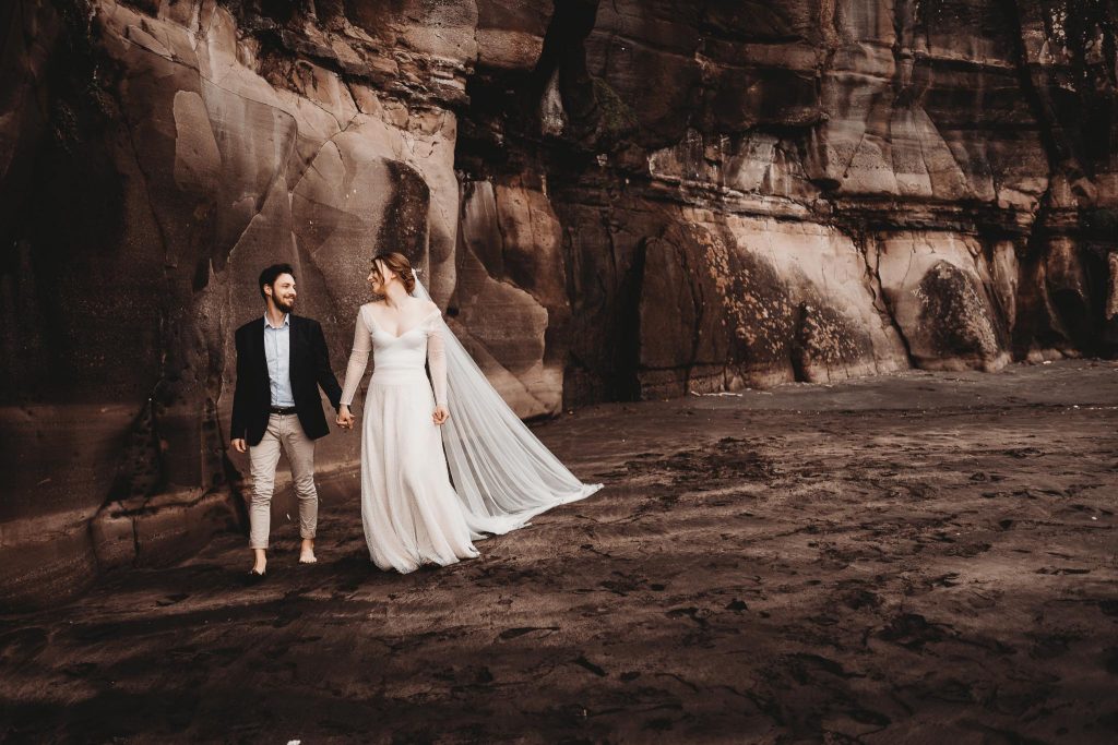 bride and groom walking on the beach - Auckland Wedding Photographer