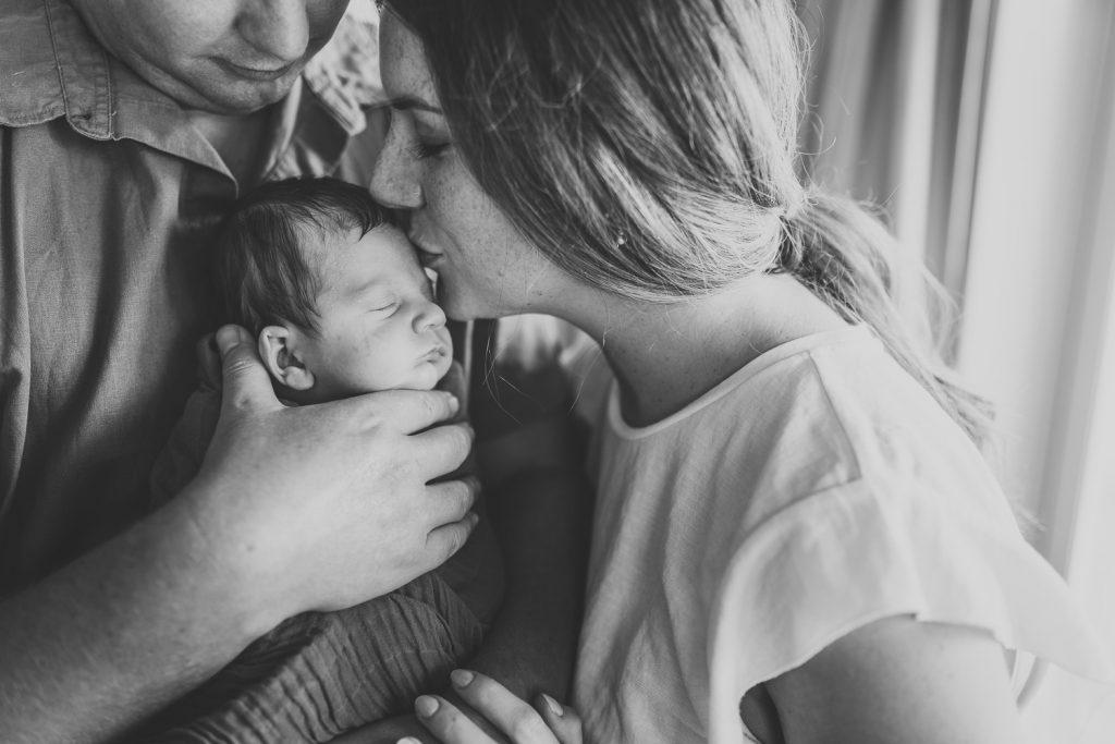 mother kissing infant
