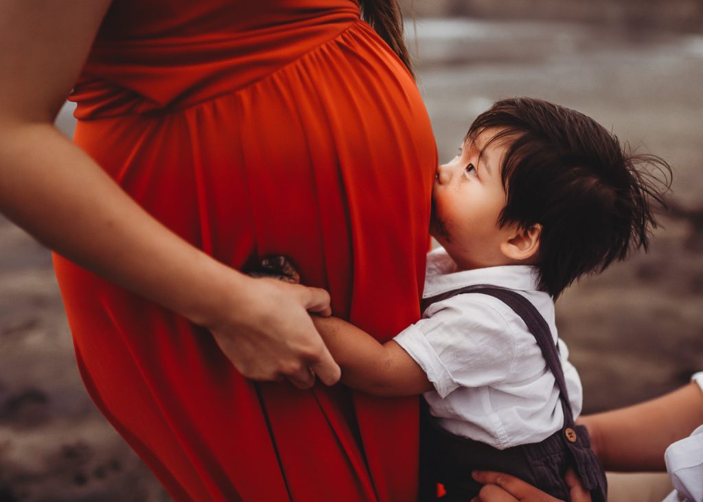 toddler kissing pregnant mom during maternity photography in auckland