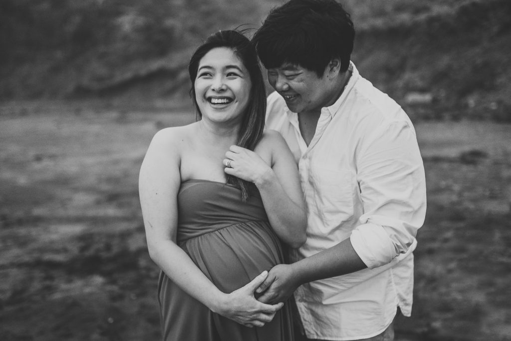 husband and pregnant wife are smiling during maternity photography in auckland