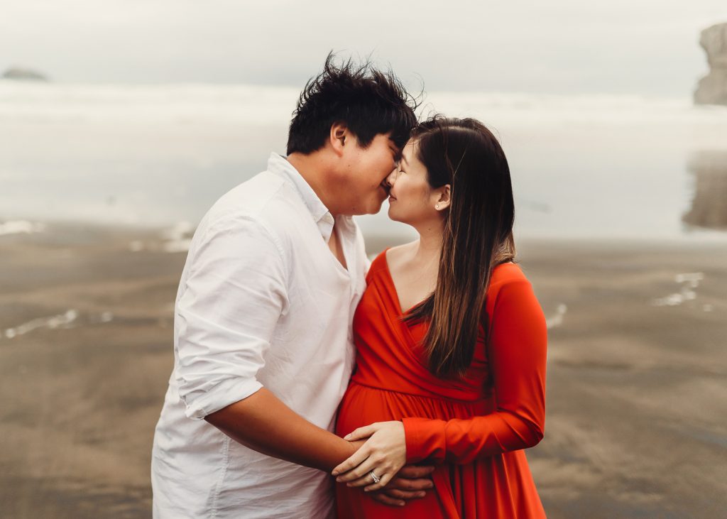 pregnant women and husband kissing each other during maternity photography in auckland