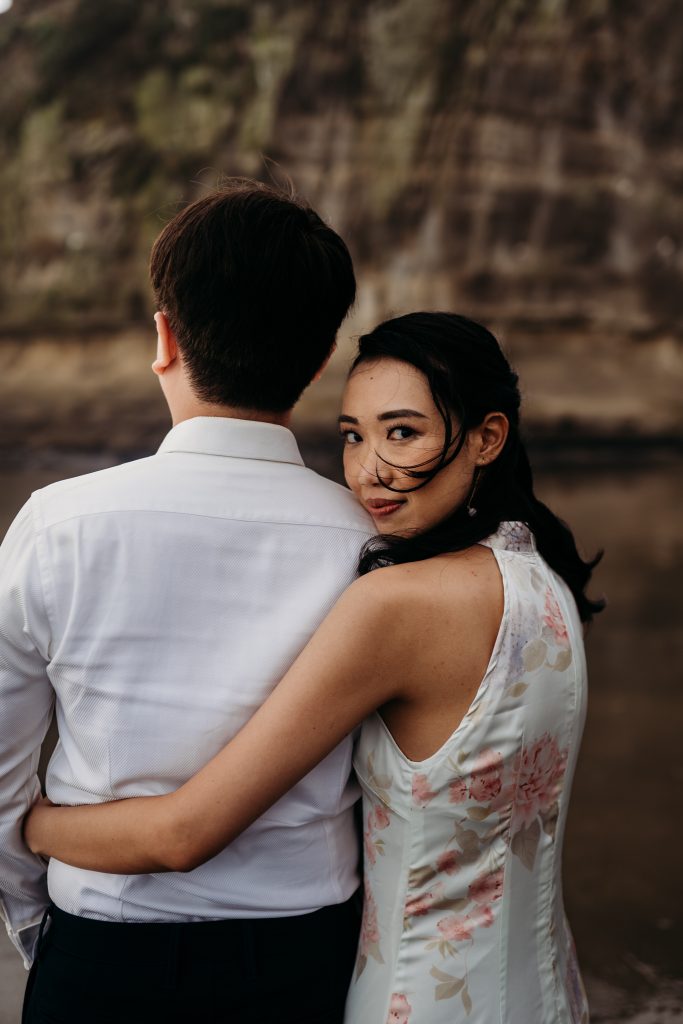 Lishan and Ernest run hand-in-hand along the shoreline of Muriwai Beach, celebrating the joy of their honeymoon.