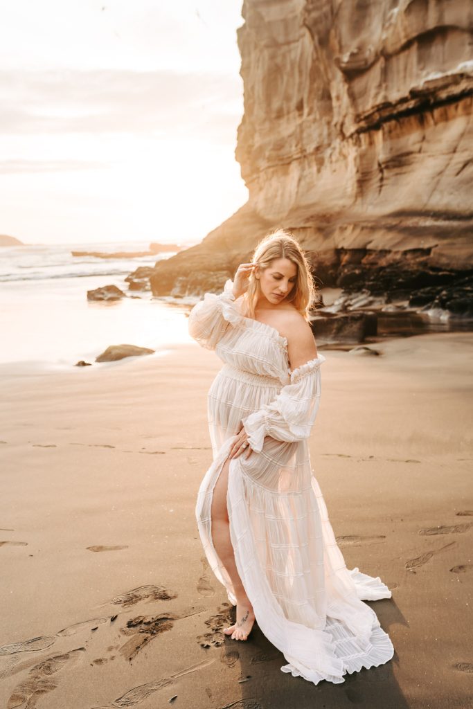 Auckland maternity photography: Elegant silhouette of a pregnant woman overlooking the Auckland cityscape at sunset.