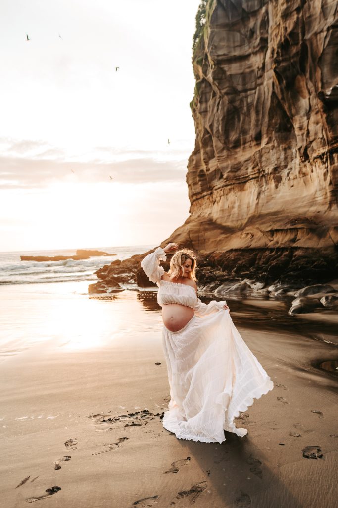 Auckland maternity photoshoot: Joyful expecting parents embrace in a field of wildflowers in Auckland.