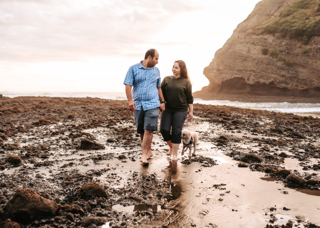 Bethells Beach anniversary shoot: Mas and Huda, bathed in the golden light of sunset, share a tender moment on the beach.